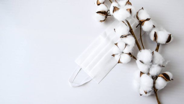 Pamut növény virág védő orvosi fehér arc maszk fehér alapon. Sebészeti maszk, orvosi maszk. Maradj otthon higiénikus karantén koncepció. A koronavírus védelmére használják D - Fotó, kép