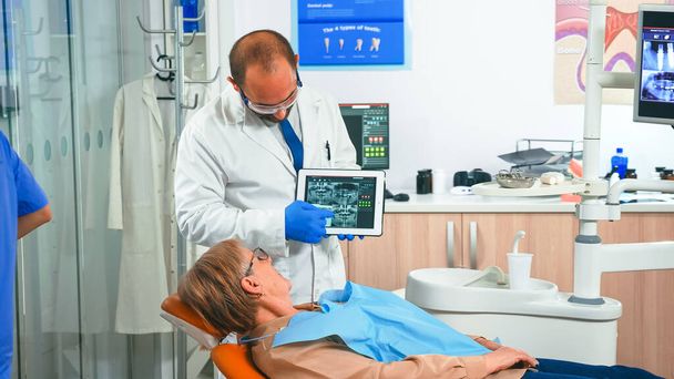 Orthodontist in gloves holding tablet suggesting treatment - Photo, Image