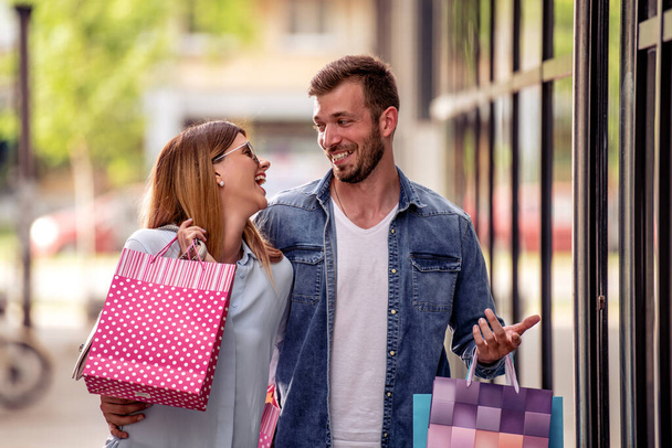 Jeune couple profitant dans le shopping ensemble, ils tenant des sacs à provisions. - Photo, image