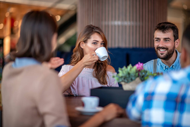 Gençler kafede oturup birlikte kahve içiyorlar..  - Fotoğraf, Görsel