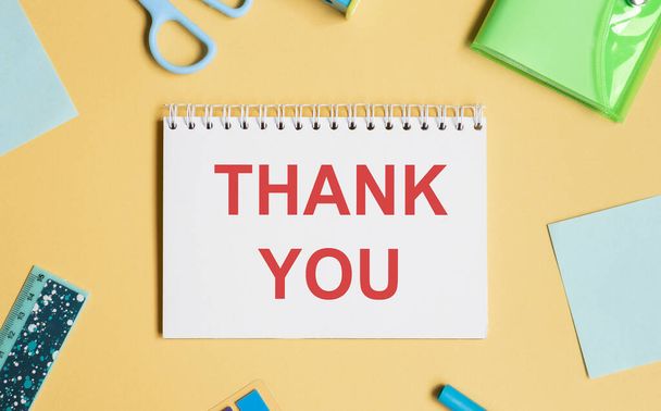Открытка "Спасибо" с канцелярскими принадлежностями на ярком столе, написание благодарственной записки - Фото, изображение