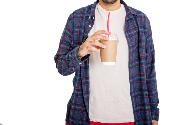Takeaway coffee concept. Young man with open checkered shirt holding a fresh beverage in a paper container with straw isolated on white background. - Fotó, kép