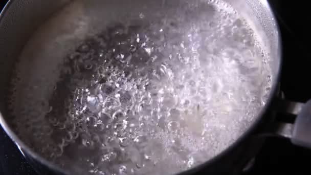 διαδικασία μαγειρέματος. Βραστό νερό σε μια κατσαρόλα στην κουζίνα. αργή κίνηση επιλεκτική εστίαση - Πλάνα, βίντεο