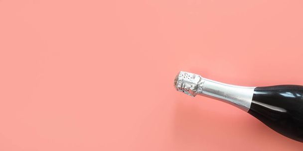 Neck of a champagne bottle with silver foil on a pastel pink background. The concept of a celebration, holiday, new year. Minimalism, copy space. - Photo, Image