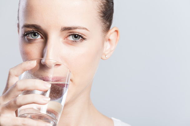 junge Frau mit lockigem Haar trinkt Wasser - Foto, Bild