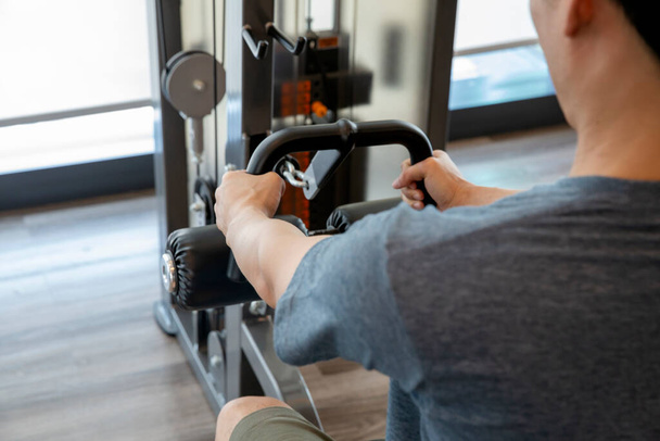 Молодой человек начинающий физические упражнения с гантели сгибая мышцы в тренажерном зале, концепция спортивной подготовки - Фото, изображение