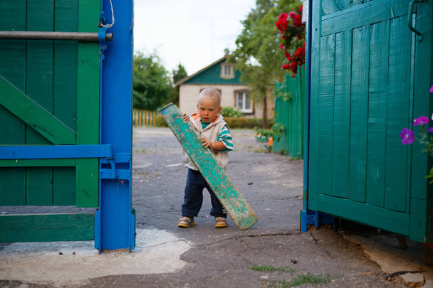the child closes the gate of the yard in the village 2020 - Photo, Image
