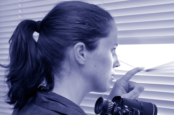 jonge vrouw op zoek via blinds - Foto, afbeelding