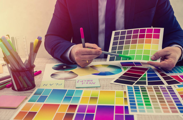 Графический дизайнер выбирает цвет из выборки в офисе. Цветные образцы. Мужские руки выбирают цвет из пробы
 - Фото, изображение