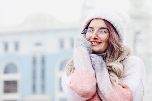 Portrait of a young pretty funny smiling girl in cold weather dressed in warm clothes and a hat. young happy woman having fun.  - Fotoğraf, Görsel