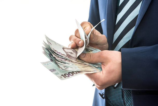 Człowiek w garniturze liczy zyski. męskie dłonie nawracają hrywien. 1000 nowych banknotów, ukraińskie pieniądze - Zdjęcie, obraz