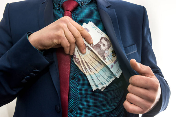 Бізнесмен бере пачку українських грошей як хабар і ховається в кишені в куртці. Корупція і трюк. Угу. 1000 нових банкнот - Фото, зображення