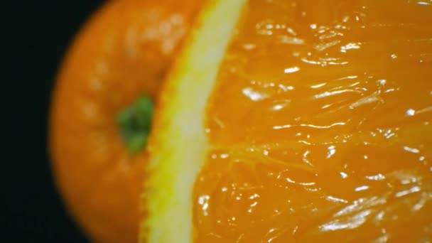Ampliar macro toma de la sección de fruta dulce naranja orgánica sobre fondo de estudio oscuro - Metraje, vídeo