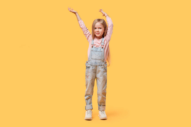 Portrait of a little blonde girl happily raised her hands up to her full height. - Фото, изображение