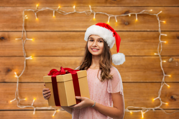 teenage girl in santa hat with christmas gift - Foto, Imagem