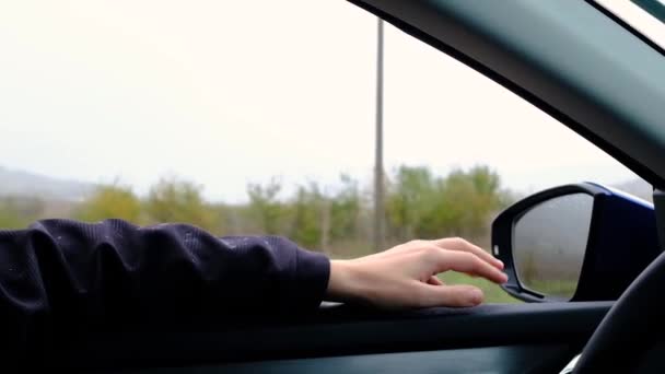 Κινηματογραφικό εμπνευσμένο βίντεο του νεαρού άνδρα που ταξιδεύει με αυτοκίνητο ή τροχόσπιτο, ανοίγει το παράθυρο για να αναπνεύσει φρέσκο αέρα της υπαίθρου, κινείται χέρι με τον άνεμο και τη βροχή. Τραγούδια μελωδία του τραγουδιού, φθινοπωρινές διακοπές vibes - Πλάνα, βίντεο