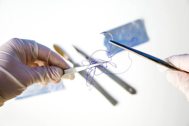 Хирургическое оборудование, скальпель, нож, шов и игла на белом фоне. Студийные съемки. - Фото, изображение