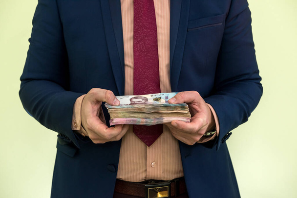 Un giovane uomo d'affari con una grossa somma di denaro. Banconote nuove ucraine UAH 1000 e 500 nelle mani di un uomo d'affari. Utile. - Foto, immagini