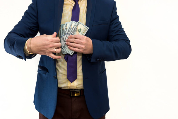 Бизнесмен получает взятку и прячет доллары в кармане пиджака. Мужские руки держат деньги, незаконное богатство. Коррупция - Фото, изображение