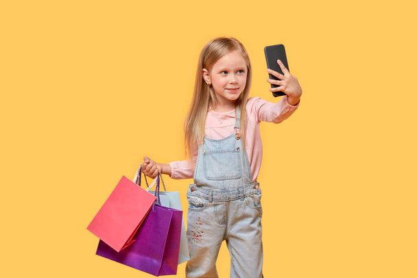 A girl takes a selfie in the hands of purchases in multi-colored bags. - Photo, Image