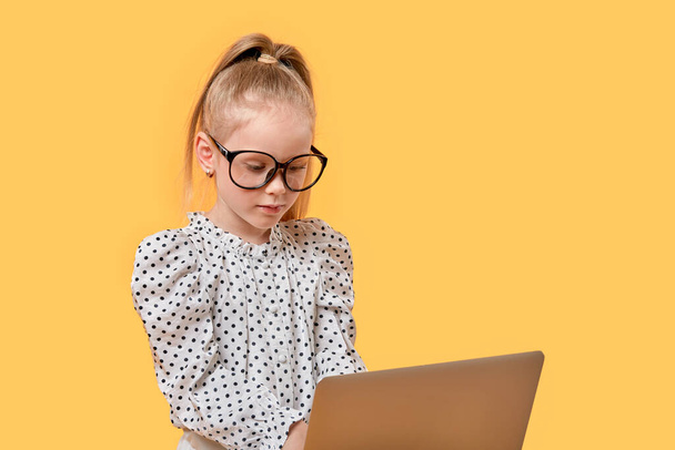 Girl child learn at home online using a laptop. Black-rimmed glasses. - Fotó, kép