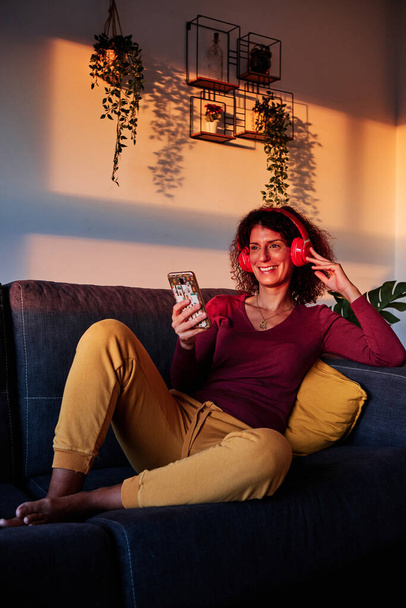 mujer escuchando música con auriculares en casa durante la cuarentena para coronavirus - Foto, Imagen