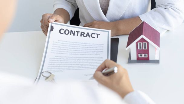 Агент по недвижимости или менеджер по продажам предложил клиентам, которые подписывают договоры купли-продажи жилья со страхованием, договор о подписании концепции договора купли-продажи. - Фото, изображение