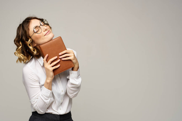 Business woman with notepad and glasses on a light background hairstyle success emotions - Zdjęcie, obraz