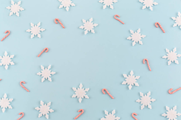 Christmas composition. Snowflakes, red and white candies on blue background. Christmas, winter, new year concept. Minimal style. Flat lay, top view, copy space. - Photo, Image