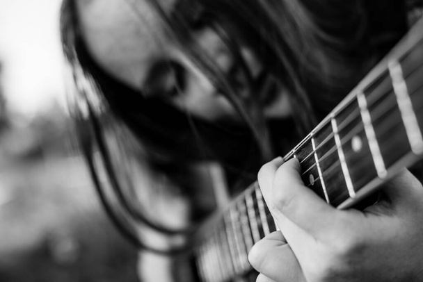 Пальці на струнах, дівчина грає на акустичній гітарі. Чорно-біла фотографія
. - Фото, зображення