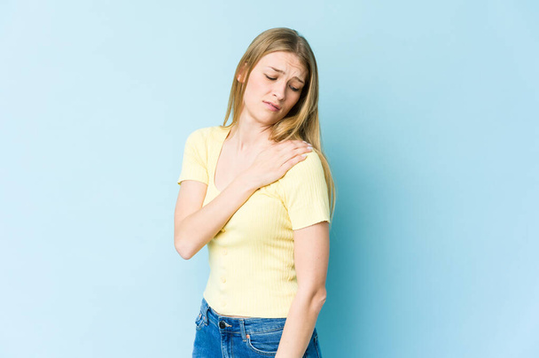 Young blonde woman isolated on blue background having a shoulder pain. - Foto, Imagen