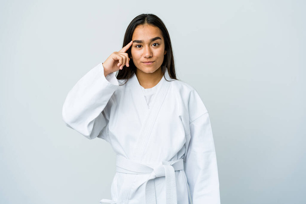 Young asian woman doing karate isolated on white background pointing temple with finger, thinking, focused on a task. - Fotografie, Obrázek