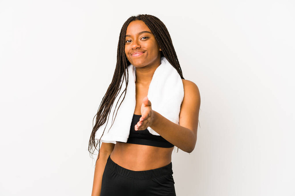 Young african american sport woman isolated stretching hand at camera in greeting gesture. - 写真・画像