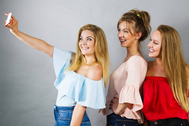 Fashionable women taking selfie self picture using smartphone having fun enjoying friends time. - Foto, afbeelding