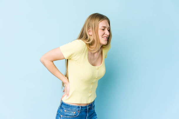 Young blonde woman isolated on blue background suffering a back pain. - Fotó, kép