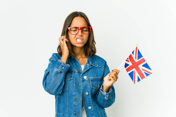 Młoda Latynoska kobieta trzymająca angielską flagę na białym tle przykrywającą uszy palcami, zestresowana i zdesperowana przez głośne otoczenie. - Zdjęcie, obraz