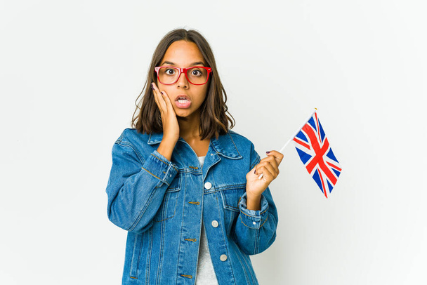 Fiatal latin nő kezében egy angol zászló elszigetelt fehér háttér lenyűgözte gazdaság másolási hely tenyéren. - Fotó, kép