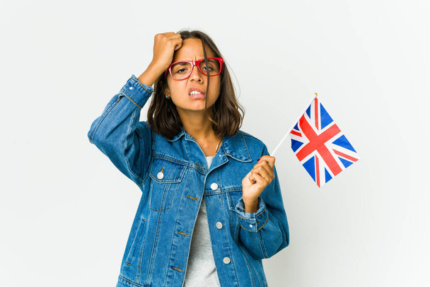 Młoda Latynoska kobieta trzyma angielską flagę na białym tle zmęczona i bardzo senna trzymając rękę na głowie. - Zdjęcie, obraz