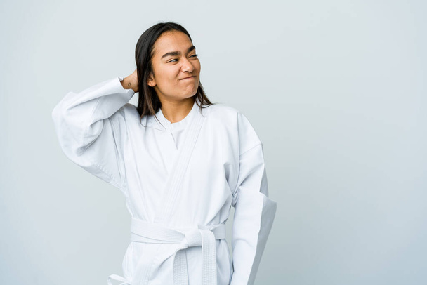 Beyaz arka planda karate yapan genç Asyalı kadın kafasının arkasına dokunuyor, düşünüyor ve bir seçim yapıyor.. - Fotoğraf, Görsel