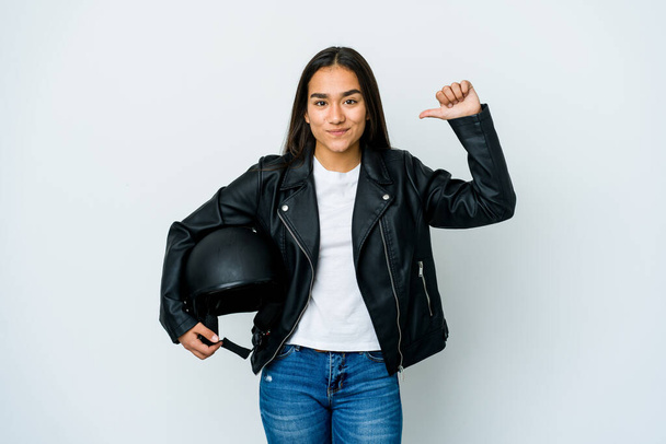 Joven mujer asiática sosteniendo un casco de moto sobre fondo aislado se siente orgulloso y seguro de sí mismo, ejemplo a seguir. - Foto, imagen
