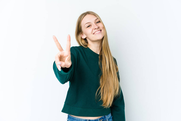 Young blonde woman isolated on white background showing victory sign and smiling broadly. - Foto, Imagen