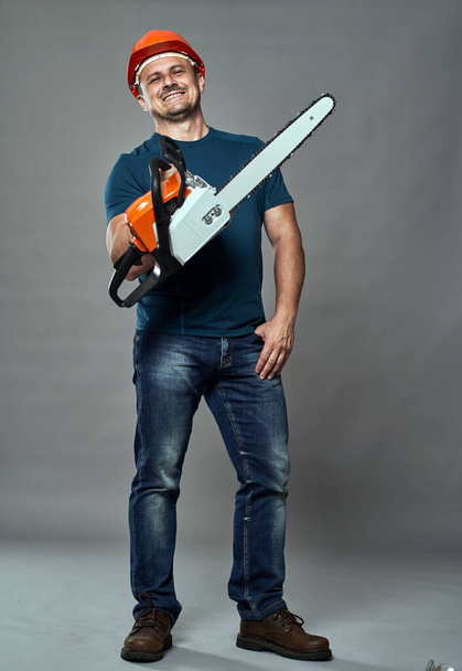 Worker in hardhat holding a chainsaw medium size - Valokuva, kuva