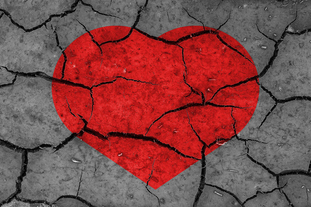 Red heart on a cracked texture. The concept of broken heart, end of love and disappointment. - Foto, Imagem