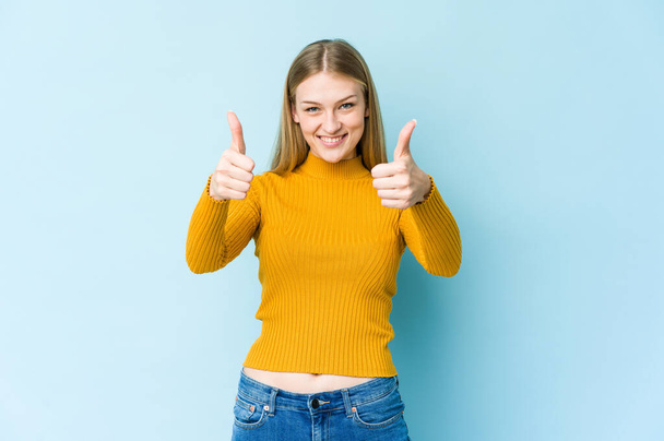 Young blonde woman isolated on blue background smiling and raising thumb up - Foto, Imagen