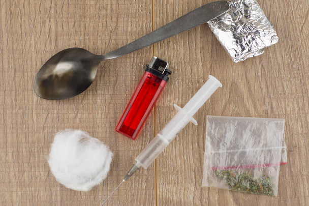 nábor nastalých injekčních uživatelů drog: injekční stříkačka, lžíce, bavlněná vlna a zapalovač ležící vedle léku Baleno v hliníkové fólii a plastovém sáčku - Fotografie, Obrázek
