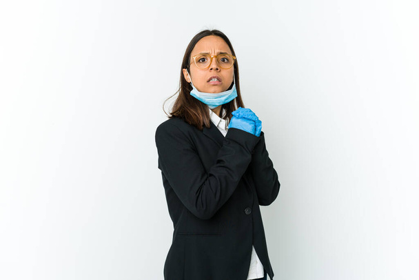 Jeune femme d'affaires latine portant un masque pour se protéger de la cohabitation isolée sur fond blanc effrayée et effrayée. - Photo, image