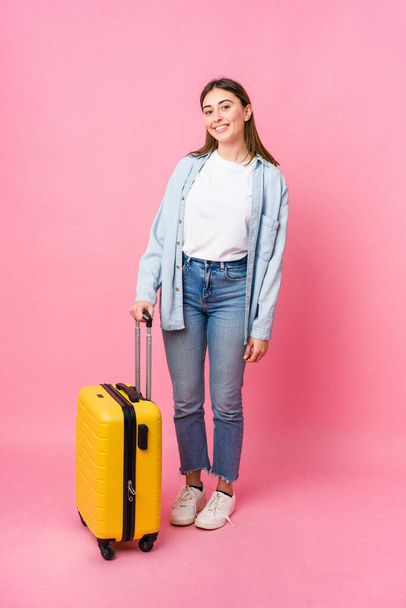 Nuori valkoihoinen nainen menossa matkustaja eristetty vaaleanpunainen tausta - Valokuva, kuva