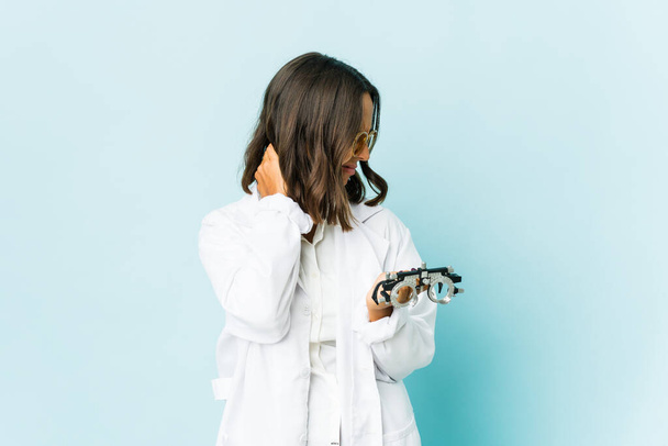 Junge Augenärztin mit lateinischem Hintergrund mit Nackenschmerzen aufgrund von Stress, massieren und berühren sie mit der Hand. - Foto, Bild