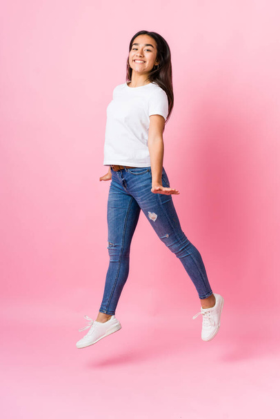 Young indian woman jumping on pink background - Photo, Image