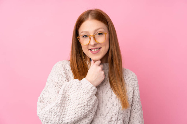 Young redhead woman over isolated pink background with glasses and smiling - Foto, Imagem